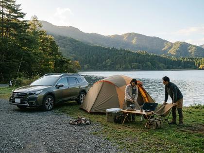 湖畔でSUVとテントを使ってキャンプを楽しむ二人。