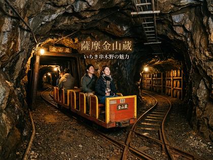 金山蔵の坑道をトロッコで進む観光客、焼酎樽が並ぶ。