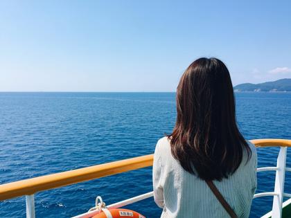 桜島フェリーの甲板から海を眺める女性の後ろ姿